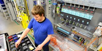 operator assembles machine in a factory - production of switch cabinets for industrial plant